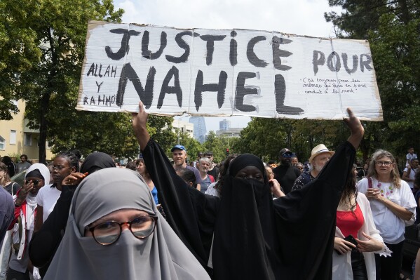 FILE - A woman shows a poster "Justice for Nahel" during a march for 17-year-old Nahel, Thursday, June 29, 2023 in Nanterre, outside Paris. Officially, race doesn't exist in France. But the killing of the French-born 17-year-old with North African roots has again exposed deep feelings about systemic racism that lie under the surface of the country's ideal of color-blind equality. (AP Photo/Michel Euler, File)