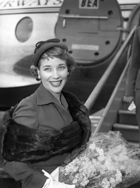 In this file photo dated July 1, 1957, Sylvia Syms prepares to leave London Airport for Berlin to attend the Film Festival, in which her picture 'Woman in a Dressing Gown' is being shown as the official British entry. Actress Sylvia Syms, who starred in classic British films including “Ice Cold in Alex” and “Victim,” has died, her family said Friday, Jan. 27, 2023. She was 89. (PA via AP)