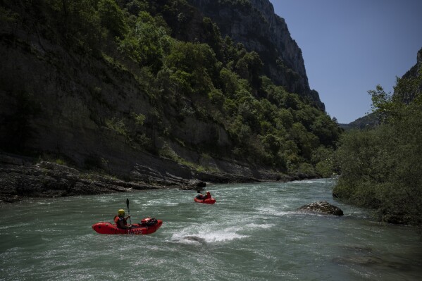 Tourists practice packrafting along the Verdon Gorge in southern France, Monday, June 19, 2023. Human-caused climate change is lengthening droughts in southern France, meaning the reservoirs are increasingly drained to lower levels to maintain the power generation and water supply needed for nearby towns and cities. It's concerning those in the tourism industry, who are working out how to keep their lakeside businesses afloat. (AP Photo/Daniel Cole)