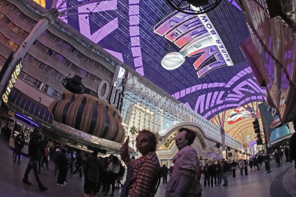 Street performers work beneath signage for Super Bowl 58 at the Fremont Street Experience Saturday, Feb. 10, 2024 in Las Vegas. The Kansas City Chiefs will play the NFL football game against the San Francisco 49ers Sunday. (AP Photo/Charlie Riedel)