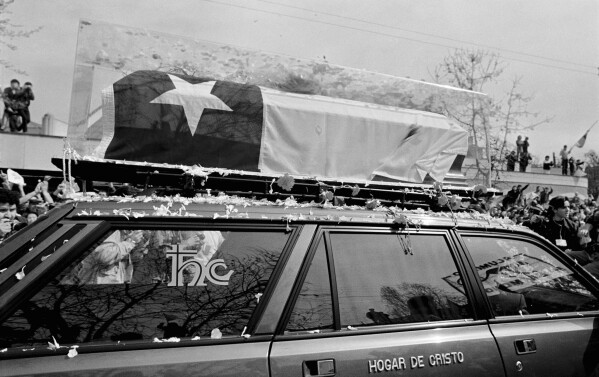 The body of ousted Chilean President Salvador Allende is transported to the General Pantheon along the main Alameda avenue in Santiago, Chile, Sept. 4, 1990, for presidential honors and reburial. Allende's remains were previously in an unmarked grave in Viña del Mar after 17 years. (AP Photo/Marco Ugarte)