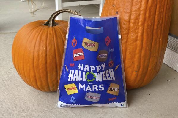 A bag distributed by Mars - the maker of Snickers and M&M's - for recycling candy wrappers is positioned between pumpkins in Ann Arbor, Mich., on October 19, 2022. The bags can be filled with wrappers and packaging from any brand and mailed free to a specialty recycler in Illinois. (AP Photo/Dee-Ann Durbin)
