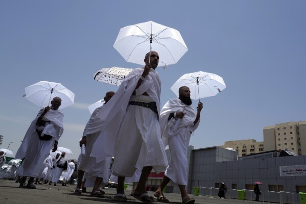 Muslim pilgrims walk, holding their umbrellas at the Mina tent camp, in Mecca, Saudi Arabia, during the annual hajj pilgrimage, Monday, June 26, 2023. Muslim pilgrims are converging on Saudi Arabia's holy city of Mecca for the largest hajj since the coronavirus pandemic severely curtailed access to one of Islam's five pillars. (AP Photo/Amr Nabil)