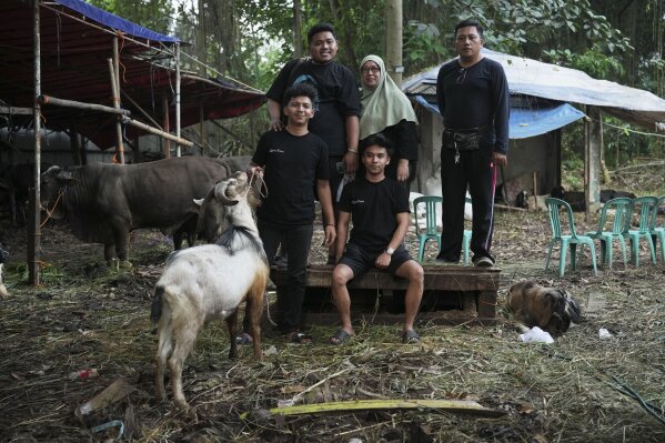 Nina Herlina, center, poses for a photo with her workers at her livestock stall in Jakarta, Indonesia, Monday, June 2, 2025. (AP Photo/Achmad Ibrahim)
