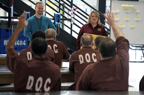 Prison psychological specialists Christine Ransom, top right, and Randy Kulesza, top left, lead a group session for inmates, Dec. 14, 2023, in the Neurodevelopmental Residential Treatment Unit at Pennsylvania's State Correctional Institution in Albion, Pa. The prison unit is helping men with autism and their intellectual and developmental disabilities stay safe behind bars while learning life skills. The unit is the first in the state and one of only a handful nationwide. (AP Photo/Gene J. Puskar)