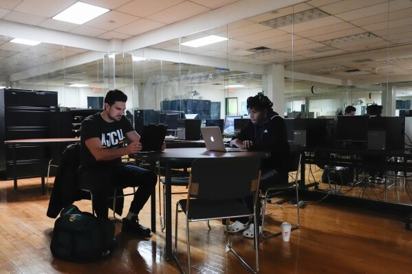 Damon LaSalle, left, studies with a teammate before volleyball practice at New Jersey City University, Friday, Feb. 21, 2025, in Jersey City, N.J. (AP Photo/Julia Demaree Nikhinson)