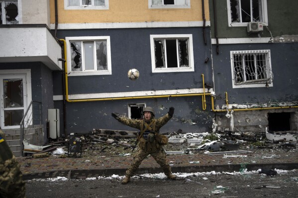 A Ukranian soldier eyes a soccer ball during a pick-up game in Irpin, on the outskirts of Kyiv, Ukraine, Saturday, April 2, 2022. (AP Photo/Rodrigo Abd)