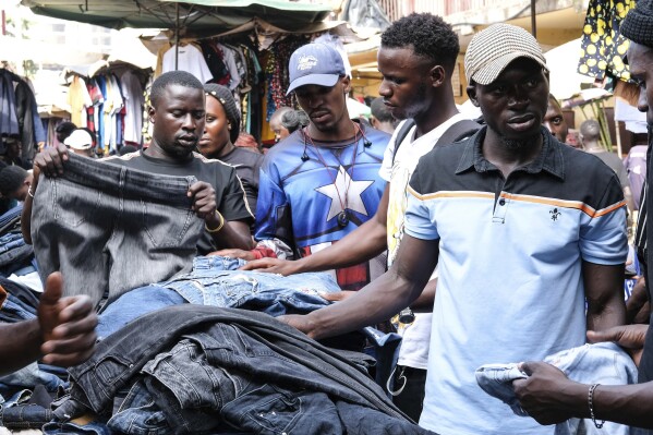 Ugandans buy second hand clothes at Owino Market, in Kampala, Uganda, Friday, Sept. 15, 2023. Jostling for space, human bodies mingle in the crowded footpaths crisscrossing this expansive open market in the Ugandan capital. The marketgoers are mostly looking for second-hand clothing, from underwear that feels new between hands to shoes that customers try on while being pushed to make way for others. (AP Photo/Hajarah Nalwadda)