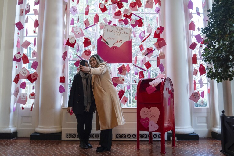 Visitors to the White House take photos in front of Valentine's Day decorations in the East Landing, Wednesday, Feb. 14, 2024, in Washington. (AP Photo/Evan Vucci)