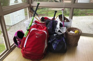 In this April 14, 2020, photo, baseball and softball bags for Colin and Catherine Graves lie untouched in Monroeville, Pa. The spring seasons for both children's youth leagues are on hold and in danger of being canceled due to the COVID-19 pandemic. (AP Photo/Will Graves)