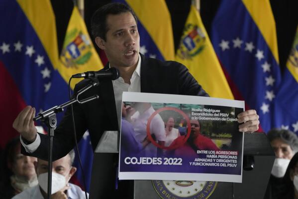 Venezuelan opposition leader Juan Guaido shows an image of a member of the ruling party that he claims was one of the persons that attacked him last Saturday, during a press conference in Caracas, Venezuela, Tuesday, June 14, 2022. (AP Photo/Ariana Cubillos)