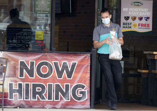 FILE - In this Sept. 2, 2020 file photo, a customer wears a face mask as they carry their order past a now hiring sign at an eatery in Richardson, Texas.  On Thursday, Nov. 5, the number of Americans seeking unemployment benefits fell slightly last week to 751,000, a still-historically high level that shows that many employers keep cutting jobs in the face of the accelerating pandemic. (AP Photo/LM Otero, File)