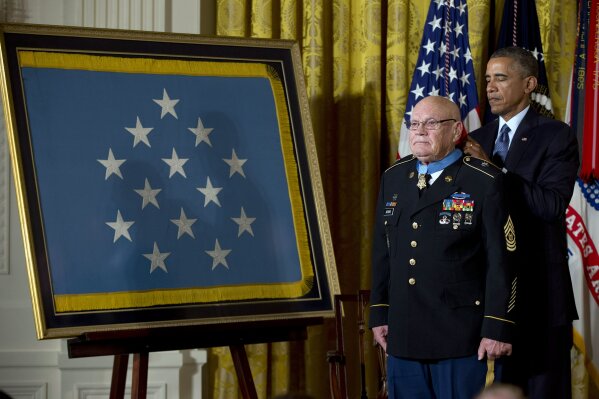 FILE- In this Sept. 15, 2014 file photo, President Barack Obama bestows the Medal of Honor on retired Army Command Sgt. Maj. Bennie G. Adkins in the East Room of the White House in Washington. Adkins, deployed three times to Vietnam with the Special Forces, was being recognized for actions during his second combat tour, in 1966, when he ran wounded through enemy fire to drag injured comrades to safety. Adkins died of coronavirus on April 17, 2020, at the age of 86. (AP Photo/Carolyn Kaster)