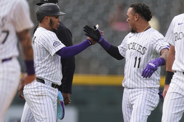 Colorado Rockies' Thairo Estrada, left, congratulates teammate Orlando Arcia (11) after Arcia's walkoff single to drive in two runs in the ninth inning of a baseball game against the San Francisco Giants, Thursday, June 12, 2025, in Denver. (AP Photo/David Zalubowski)