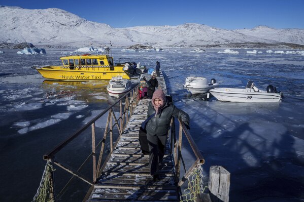 Passengers walk on a pier after arriving in Kapisillit village in Greenland, March 6, 2025. (AP Photo/Evgeniy Maloletka)