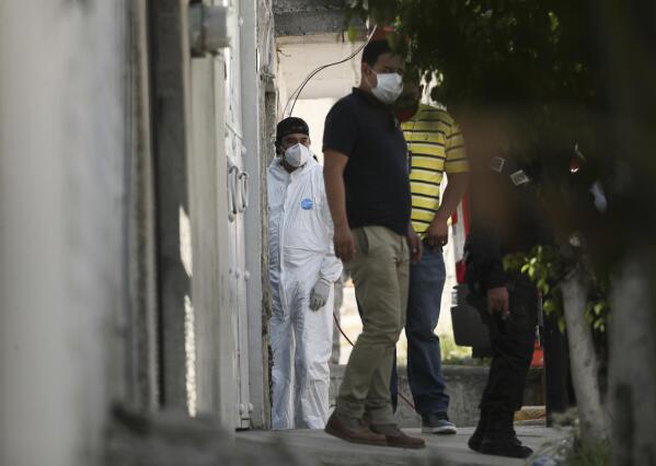 A forensic investigator stands at the entrance of a house where police found bones under the floor in the Atizapan municipality of the State of Mexico, Thursday, May 20, 2021. Police have turned up bones and other evidence under the floor of the house where a man was arrested for allegedly stabbing a woman to death and hacking up her body. (AP Photo/Fernando Llano)