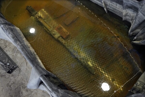 A recovered machine gun from a P-39 Airacobra is seen in a chemical solution, Thursday, Aug. 17, 2023 in Detroit. A team of divers have been trolling Lake Huron off Michigan's Thumb for several weeks each of the past few years searching for scattered pieces of aviation — and Black military — history. Their target is the wreckage of a World War II-era fighter plane flown by a member of the famed Tuskegee airmen that crashed during training nearly 80 years ago near Port Huron, about 60 miles northeast of Detroit. (AP Photo/Carlos Osorio)