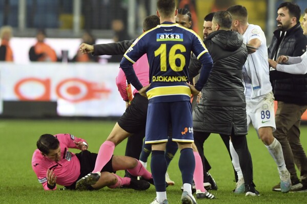 Referee Halil Umut Meler, left, falls down after being punched by MKE Ankaragucu president Faruk Koca, barely seen second left, at the end of the Turkish Super Lig soccer match between MKE Ankaragucu and Caykur Rizespor in Ankara, Monday, Dec. 11, 2023. The Turkish Football Federation has suspended all league games in the country after a club president punched the referee in the face at the end of a top-flight match. Koca was arrested Tuesday, Dec. 12, 2023 along with two other people on charges of injuring a public official following questioning by prosecutors. (Abdurrahman Antakyali/Depo Photos via AP)