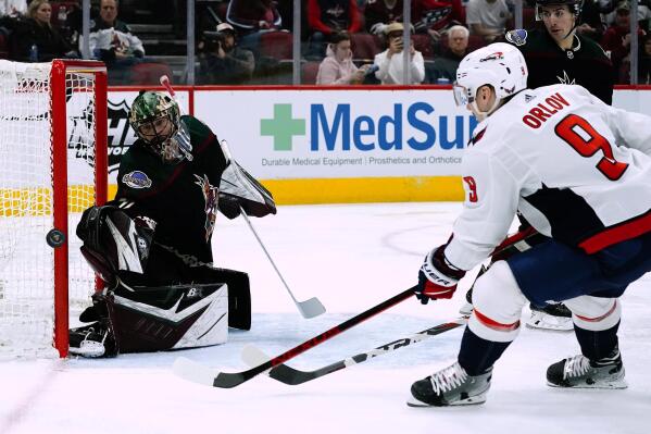 Washington Capitals defenseman Dmitry Orlov (9) shoots wide of Arizona Coyotes goaltender Karel Vejmelka, left, as Coyotes defenseman Cam Dineen, back right, watches during the second period of an NHL hockey game Friday, April 22, 2022, in Glendale, Ariz. (AP Photo/Ross D. Franklin)