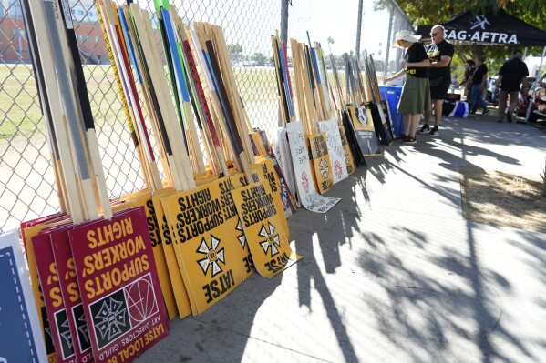 Striking SAG-AFTRA members pick out signs for a picket line outside Netflix studios, Wednesday, Nov. 8, 2023, in Los Angeles. (AP Photo/Chris Pizzello)
