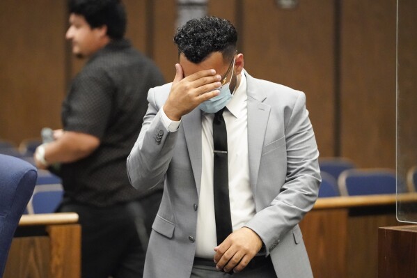 FILE - Kevin Aziz Riad shields his face as he stands in court, Aug. 15, 2023, in Compton, Calif. Aziz Riad, a Tesla driver who pleaded guilty to two counts of vehicular manslaughter with gross negligence for a 2019 car crash in a Los Angeles suburb, will pay more than $23,000 in restitution. The restitution wraps up a case believed to be the first time in the U.S. prosecutors brought felony charges against a motorist who was using a partially automated driving system. (AP Photo/Ryan Sun, File)