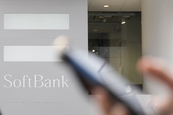 FILE - A pedestrian carries a phone past a SoftBank logo in Tokyo on May 12, 2022. Japanese technology conglomerate SoftBank Group returned to profitability in October-December after four straight quarters in the red, the company said Thursday, Feb. 8, 2024. (AP Photo/Shuji Kajiyama, File)