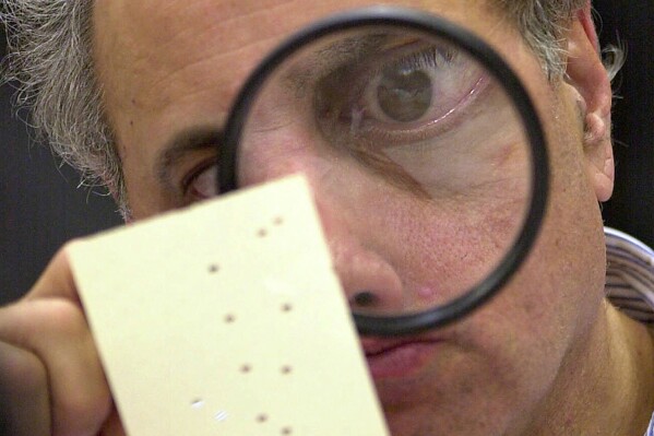 Broward County, Fla. canvassing board member Judge Robert Rosenberg uses a magnifying glass to examine a disputed ballot at the Broward County Courthouse in Fort Lauderdale, Fla., Nov. 24, 2000. (AP Photo/Alan Diaz, File)