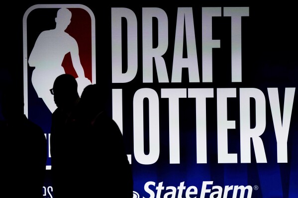 People walk by a sign during the NBA basketball draft lottery in Chicago, Tuesday, May 16, 2023. (AP Photo/Nam Y. Huh, File)