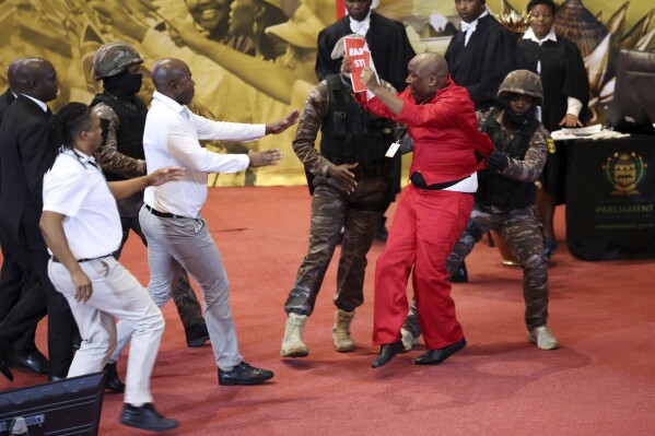 FILE - Opposition Economic Freedom Fighters party leader Julius Malema, center right, is removed by presidential task force as South African President Cyril Ramaphosa attempts to deliver his State of the Nation address to MP's in Cape Town, South Africa, on Feb. 9, 2023. The leaders of a boisterous South African opposition party have had their ban from attending a speech this week by President Cyril Ramaphosa to open the new parliamentary session upheld by a court. The leader, deputy leader and four other officials with the Economic Freedom Fighters — the third biggest party in Parliament — will not be allowed at Thursday's State of the Nation Address. (Esa Alexander/Pool Photo via AP, File)