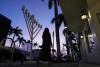 A woman in conservative dress walks past a menorah standing outside a Jewish synagogue ahead of the start of Hanukkah, in Miami Beach, Fla., Friday, Dec. 1, 2023. Daily life for many Jews has been upended by the surprise attack on Oct. 7 in Israel, when Hamas militants killed about 1,200, mostly civilians, and by the rise in antisemitism worldwide during the ensuing war, in which more than 15,800 Palestinians have died. (APPhoto/Rebecca Blackwell)