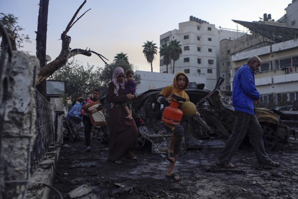 Palestinians carry belongings as they leave al-Ahli hospital, which they were using as a shelter, in Gaza City, Wednesday, Oct. 18, 2023. (AP Photo/Abed Khaled)