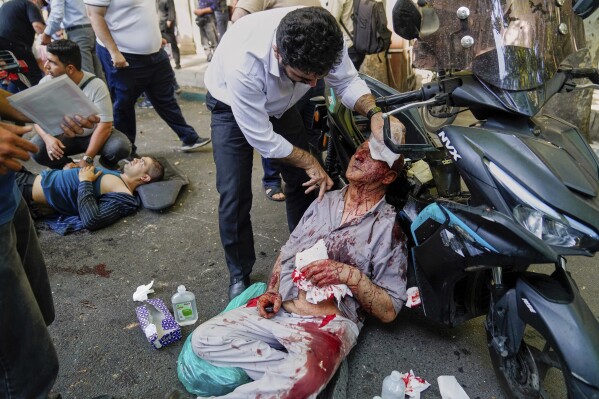 An injured man is assisted in the street after an explosion in downtown Tehran, amid Israel's three-day campaign of strikes against Iran, Sunday, June 15, 2025. (AP Photo/Amir Kholousi/ISNA)