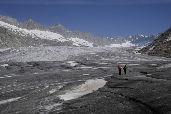 Matthias Huss, of the Federal Institute of Technology in Zurich and glacier monitoring group GLAMOS, and Monica Ursina Jaeger arrive at the Rhone glacier near Goms, Switzerland, June 10, 2025. (AP Photo/Matthias Schrader)