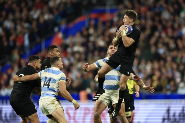 FILE - New Zealand's Beauden Barrett, top, catches the ball during the Rugby World Cup semifinal match between Argentina and New Zealand at the Stade de France in Saint-Denis, outside Paris, Friday, Oct. 20, 2023. All Blacks playmaker Barrett has re-signed with New Zealand Rugby through the 2027 World Cup. (AP Photo/Aurelien Morissard, File)