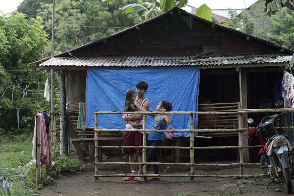 Ronnel Manjares, left, and Trisha May Noche, right, plays with their daughter Crystal outside the house of their relative in Tanauan, Batangas province, Philippines, Wednesday, July 15, 2020. Their 16-day-old son Kobe was heralded as the country's youngest COVID-19 survivor. But the relief and joy proved didn't last. Three days later, Kobe died on June 4 from complications of Hirschsprung disease, a rare birth defect. (AP Photo/Aaron Favila) (AP Photo/Aaron Favila)