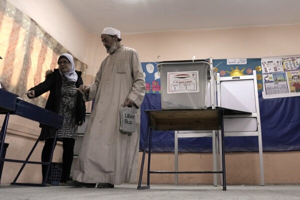 An elderly man is helped after casting his vote for the presidential elections at a polling station, in Cairo, Egypt, Sunday, Dec. 10, 2023. Egyptians began voting Sunday in a presidential election in which President Abdel Fattah el-Sissi, who faces no serious challenger, is certain to win another term, keeping him in power until 2030. (AP Photo/Amr Nabil)