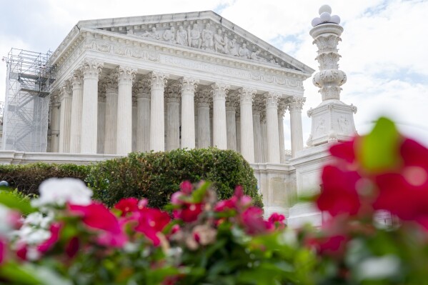 The Supreme Court is seen behind flowers, Tuesday, June 27, 2023, in Washington. The Supreme Court gave a win for the democratic principle of checks and balances in affirming that state courts can weigh in on legislative decisions affecting federal elections, but justices also left an opening for future challenges. (AP Photo/Jacquelyn Martin)