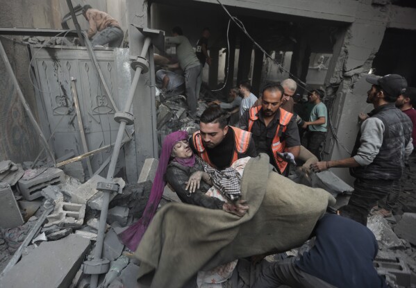 Palestinian rescuers evacuate an injured woman that was found under the rubble of a destroyed house following an Israeli airstrike in Khan Younis refugee camp, southern Gaza Strip, Saturday, Nov. 18, 2023. (AP Photo/Mohammed Dahman)