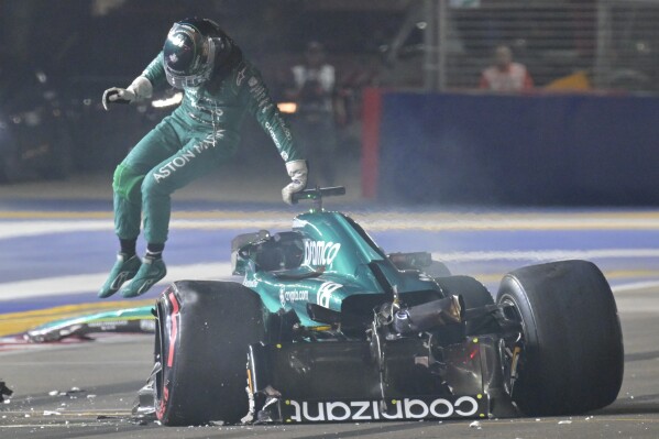 Aston Martin driver Lance Stroll of Canada jumps out from his car after a crash during the qualifying session of the Singapore Formula One Grand Prix at the Marina Bay circuit, Singapore, Saturday, Sept. 16, 2023. (Caroline Chia/Pool Photo via AP)