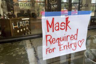 FILE - This July 28, 2021 file photo shows a sign on the door of a hair salon informing patrons that masks are required to be in the business in Kansas City, Mo.  Businesses large and small are reinstituting mask mandates and requiring vaccines of their customers as U.S. coronavirus cases rise.  (Jill Toyoshiba/The Kansas City Star via AP, File)