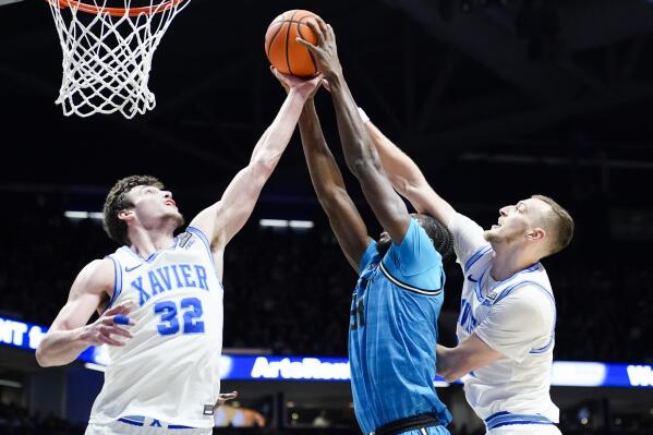 Xavier forward Zach Freemantle (32) and Xavier forward Jack Nunge, right, fight for a rebound with Georgetown center Qudus Wahab (34) during the first half of an NCAA college basketball game, Saturday, Jan. 21, 2023, in Cincinnati. (AP Photo/Joshua A. Bickel)