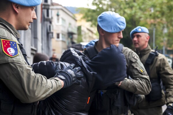 Members of the special police unit of Canton Sarajevo escort a person arrested in an operation codenamed "Black Tie" in Sarajevo, Bosnia, Monday, April 22, 2024.In a large-scale raid conducted in Bosnia and Herzegovina, law enforcement officers swarmed homes and offices of 23 persons suspected to be part of the 'inner circle' of a drug kingpin. (AP Photo/Armin Durgut)
