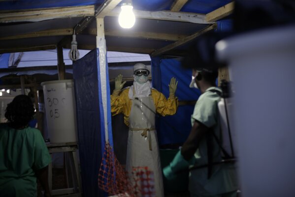 FILE- In this Nov. 20, 2014 file photo, an MSF Ebola heath worker is sprayed as he leaves the contaminated zone at the Ebola treatment centre in Gueckedou, Guinea. Guinea has officially declared an...
