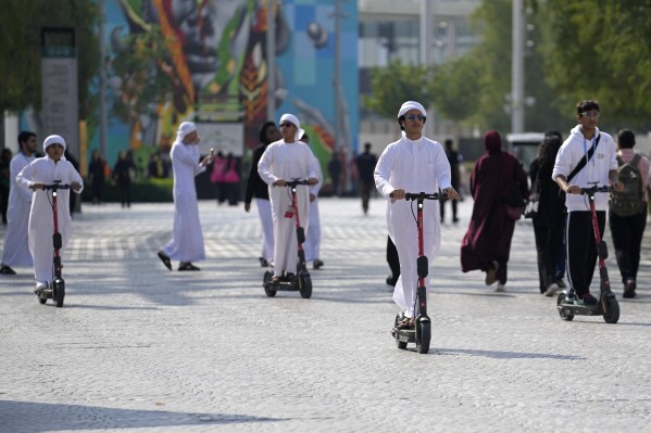 People ride an electric scooter through the COP28 U.N. Climate Summit, Dec. 8, 2023, in Dubai, United Arab Emirates. (AP Photo/Rafiq Maqbool)