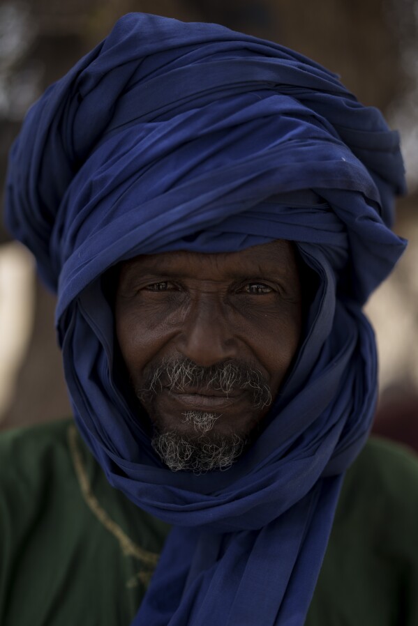 Mamadou Ba stands for a portrait at a local market near a water station known as Bem Bem, in the Matam region of Senegal, Wednesday, April. 19, 2023. For the 64-year-old herder, the difficulties surge when diseases are noticed and the arrival of veterinarians turns from preventive to treatment. "The benefits of raising livestock are having cattle and being able to live off them when the herd is good", he says. (AP Photo/Leo Correa)