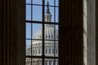 The Capitol is framed through a window in the Russell Senate Office Building as lawmakers negotiate on the emergency coronavirus response legislation, at the Capitol in Washington, Wednesday, March...
