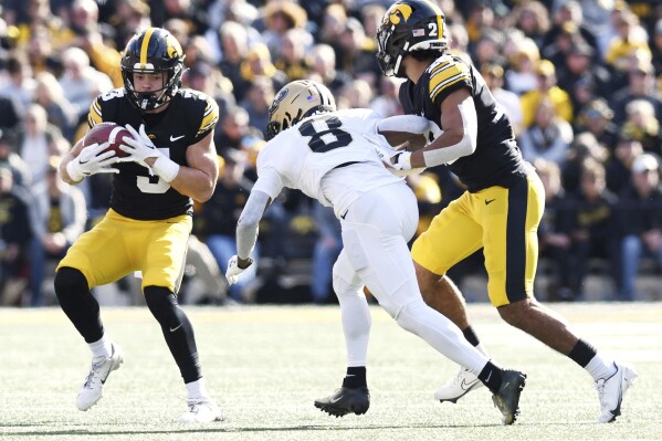 Iowa defensive back Cooper DeJean (3) intercepts a pass intended for Purdue wide receiver TJ Sheffield (8) under pressure from Iowa defensive back Sebastian Castro (29) during the first half of an NCAA college football game, Saturday, Oct. 7, 2023, in Iowa City, Iowa. (AP Photo/Cliff Jette)