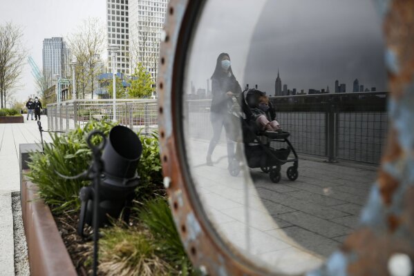 A visitor pushes a stroller while wearing a protective mask at Domino Park, Friday, May 8, 2020, in the Brooklyn borough of New York. Some parks will see stepped-up policing to stem the spread of the coronavirus, New York City Mayor Bill de Blasio said Friday. He also announced that 2,500 members of a "test and trace corps" will be in place by early June to combat the virus. (AP Photo/John Minchillo)