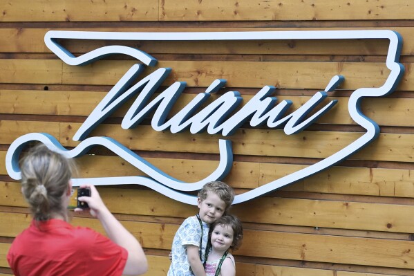 Aaron Mart, 4, and his sister Eloise, 2, whose father is an engineer for the Red Bull team, have their photo taken by their mother Anne Bachelay in front of a Formula One Miami Grand Prix auto race logo in the shape of the track, Thursday, May 1, 2025, in Miami Gardens, Fla. (AP Photo/Rebecca Blackwell)