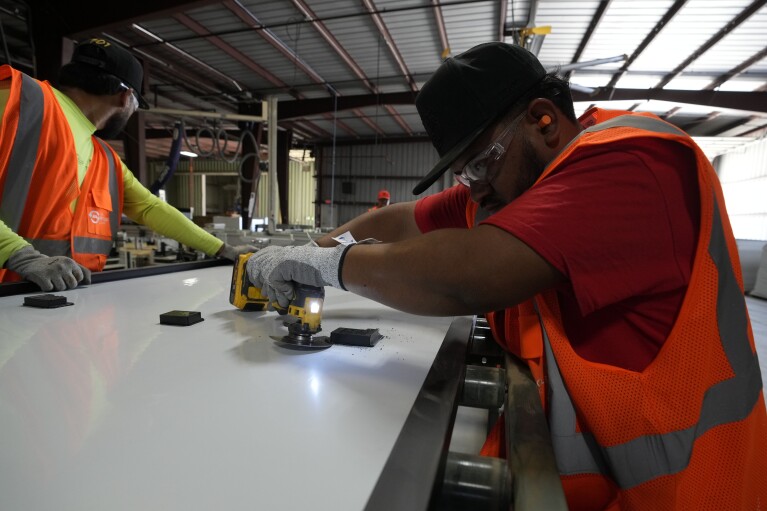 Workers take apart solar panels as they begin the recycling process at We Recycle Solar on Tuesday, June 6, 2023, in Yuma, Ariz.  (AP Photo/Gregory Bull)